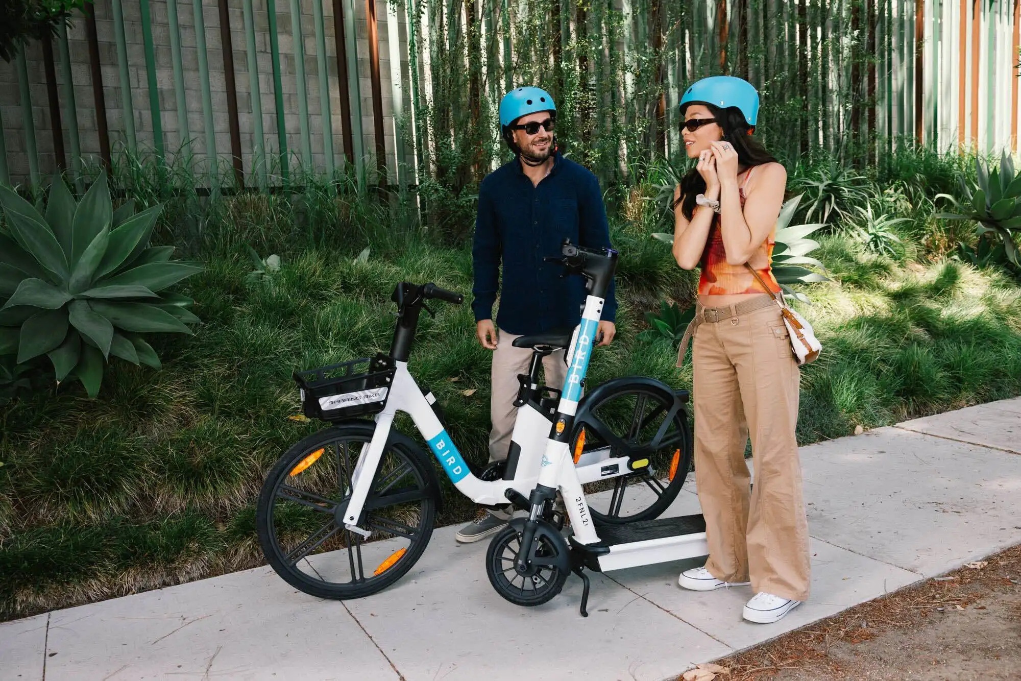 Two people standing together next to a Bird e-bike on a sunny path